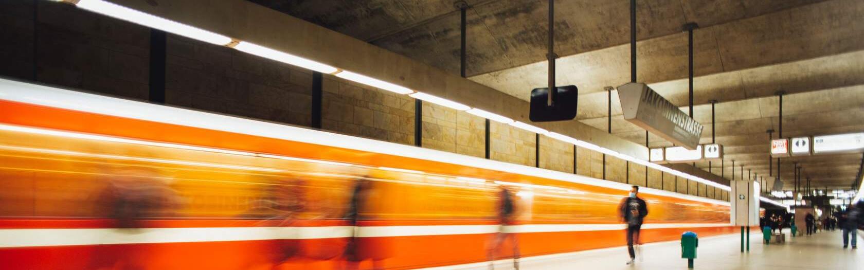 Bahnsteig mit Menschen und einer fahrenden Bahn in Bewegung und Unschärfe