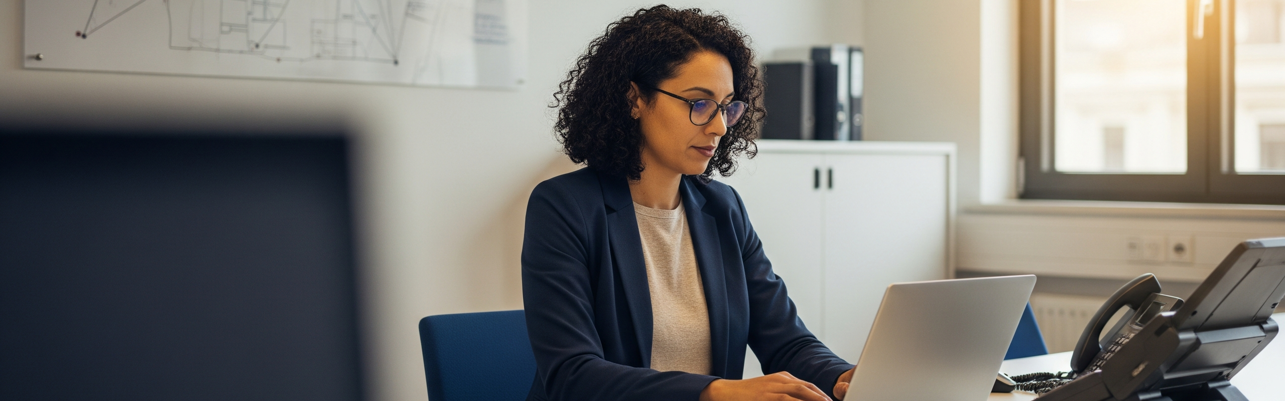 Frau sitzt vor einem Laptop im Büro.