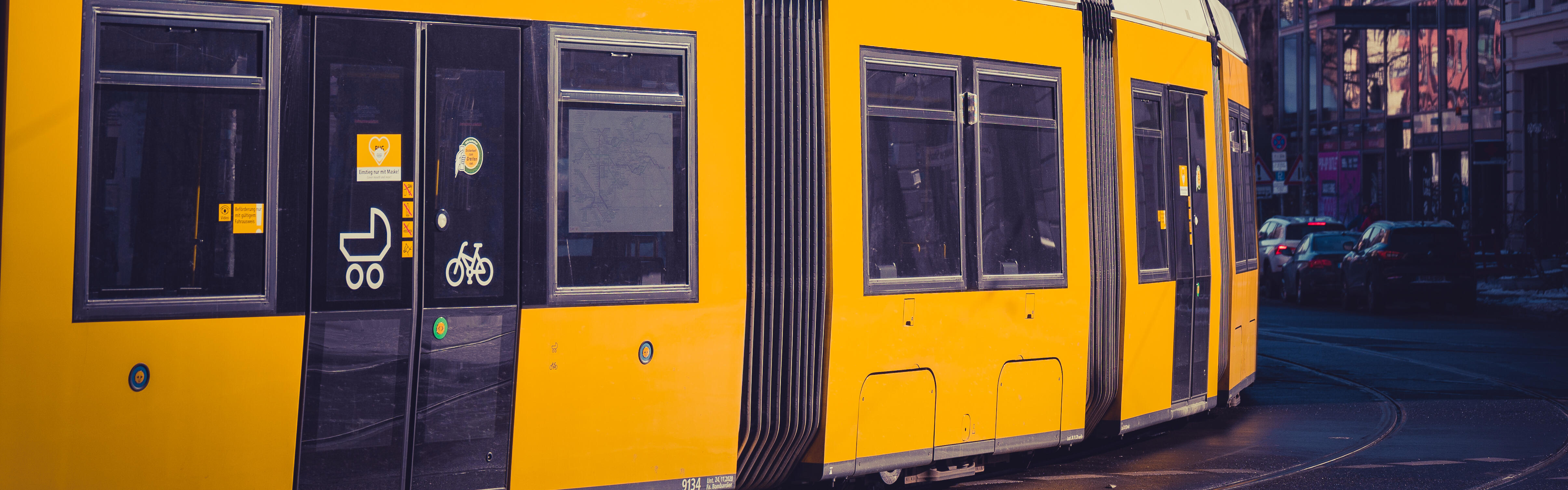 Eine gelbe Straßenbahn in der Innenstadt von Berlin, im Hintergrund der Fernsehturm.