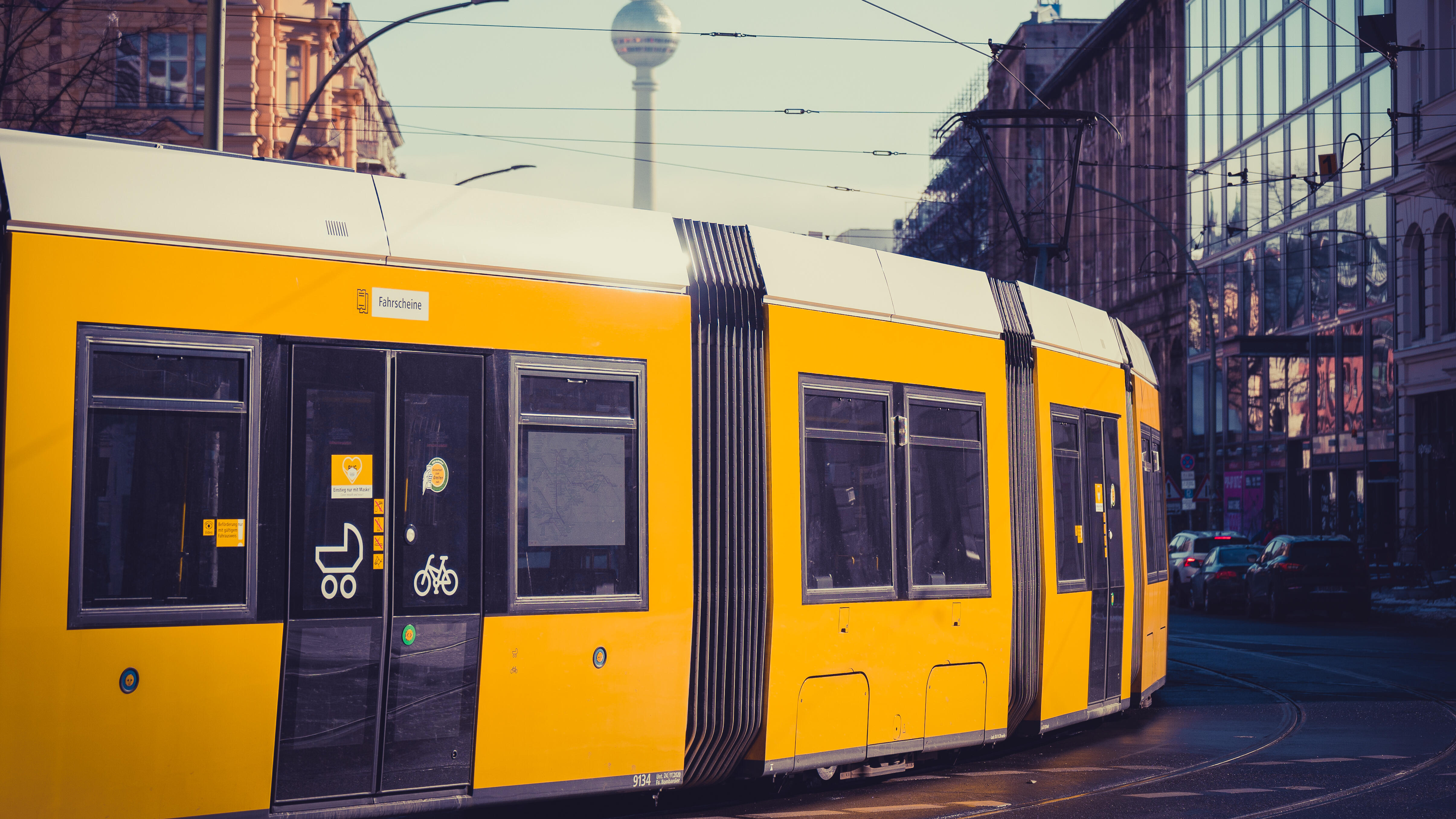 Eine gelbe Straßenbahn in der Innenstadt von Berlin, im Hintergrund der Fernsehturm.