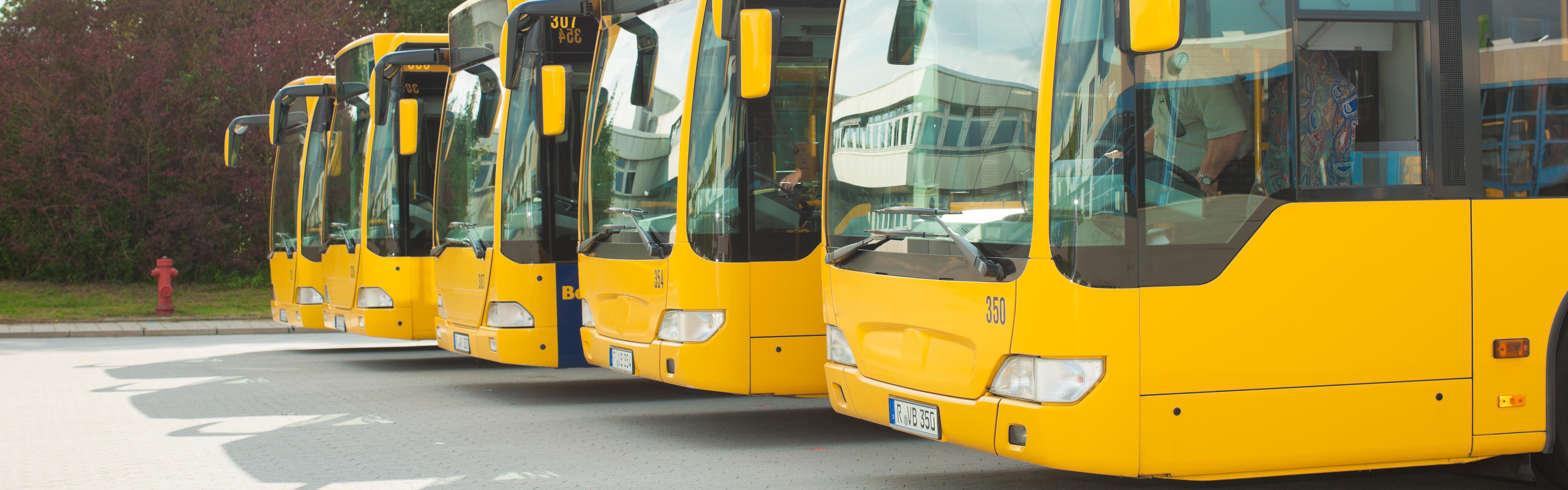 Vier gelbe Busse sind auf dem Betriebshof geparkt.