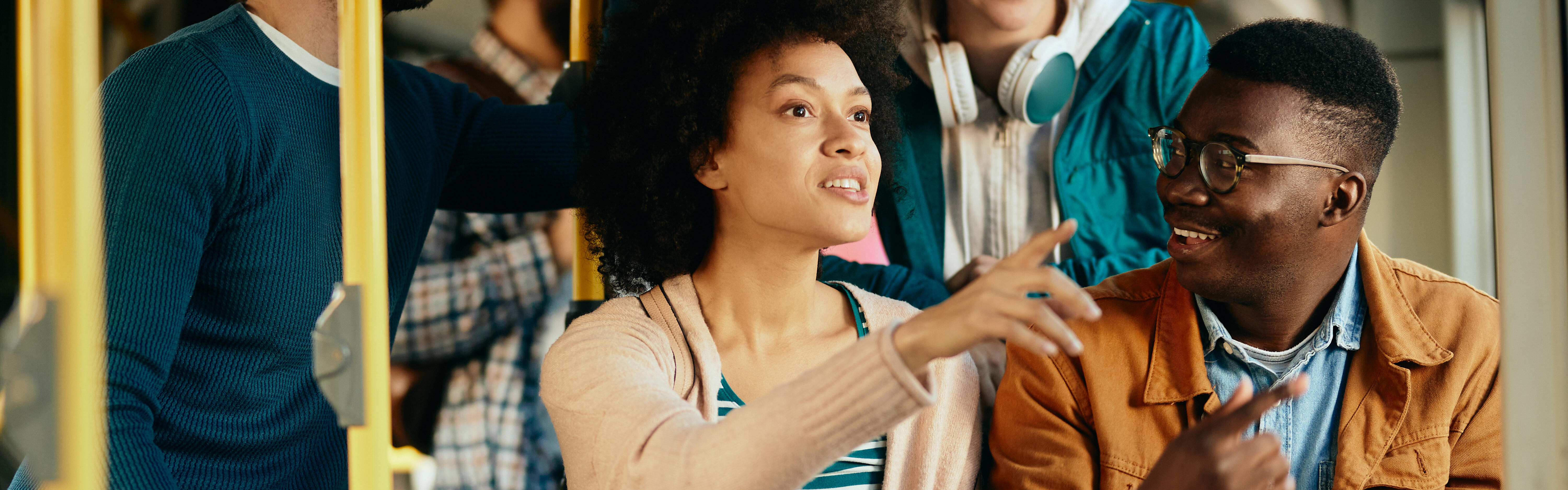 Personen mit unterschiedlicher Herkunft sitzen im Bus und unterhalten sich.