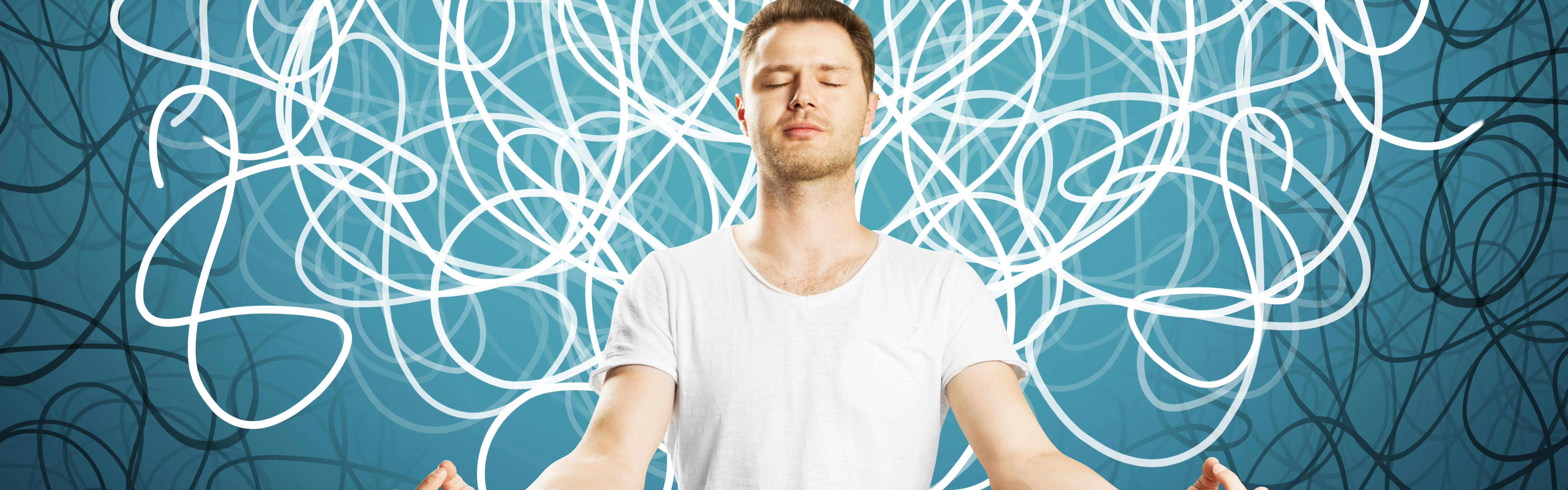 Mann in weißem T-Shirt sitzt mit geschlossenen Augen und meditiert.