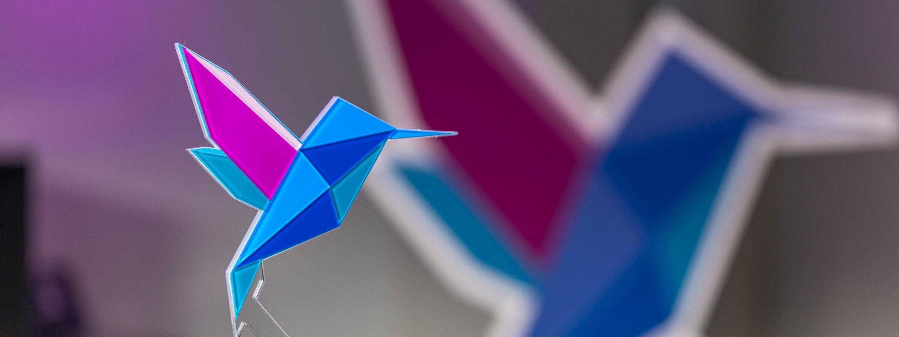 Der Mobility E-Learning Award in Form eines Kolibris mit Origami-Elementen in Blau und Lila