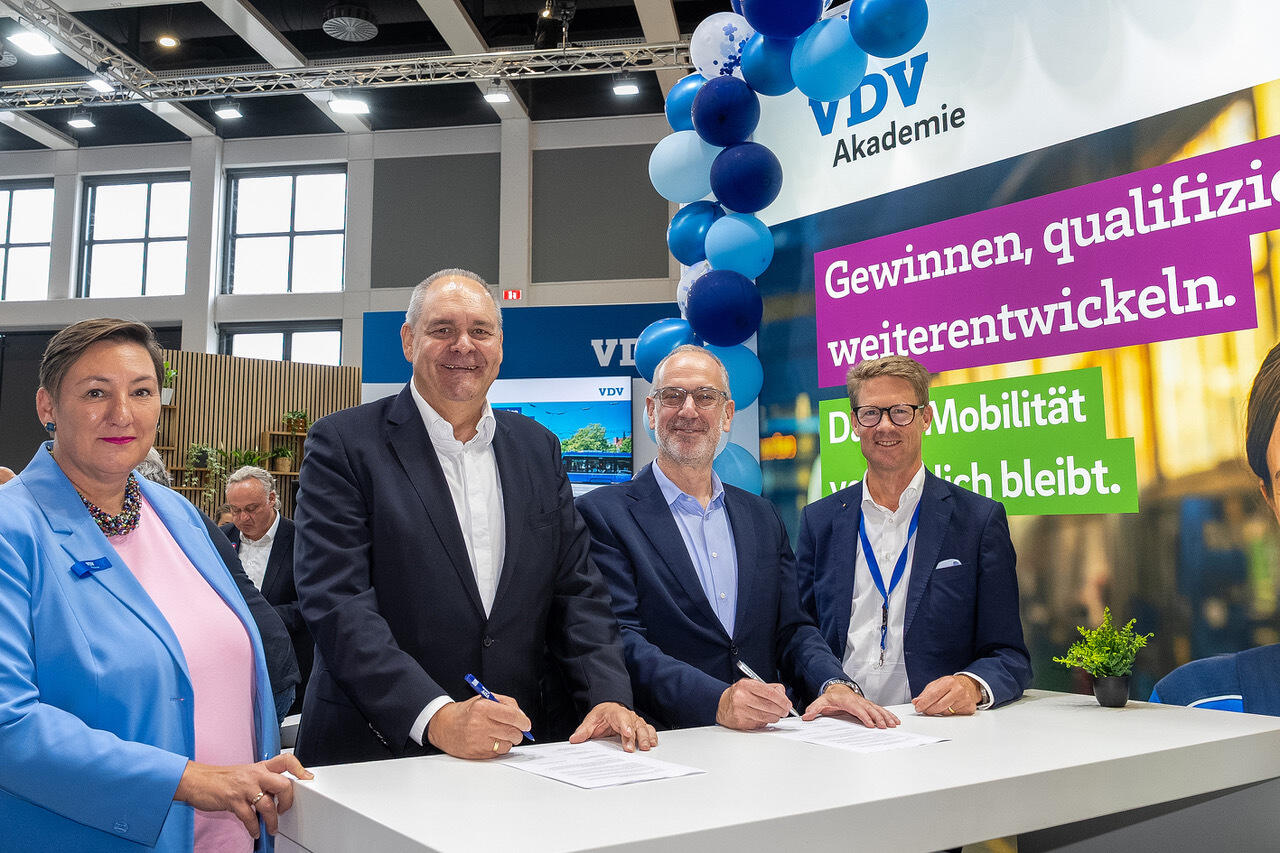 VDV-Akademie und Knorr-Bremse Trainings Akademie unterzeichnen Kooperationsvereinbarung. Vier Personen stehen und unterzeichnen die Papiere.