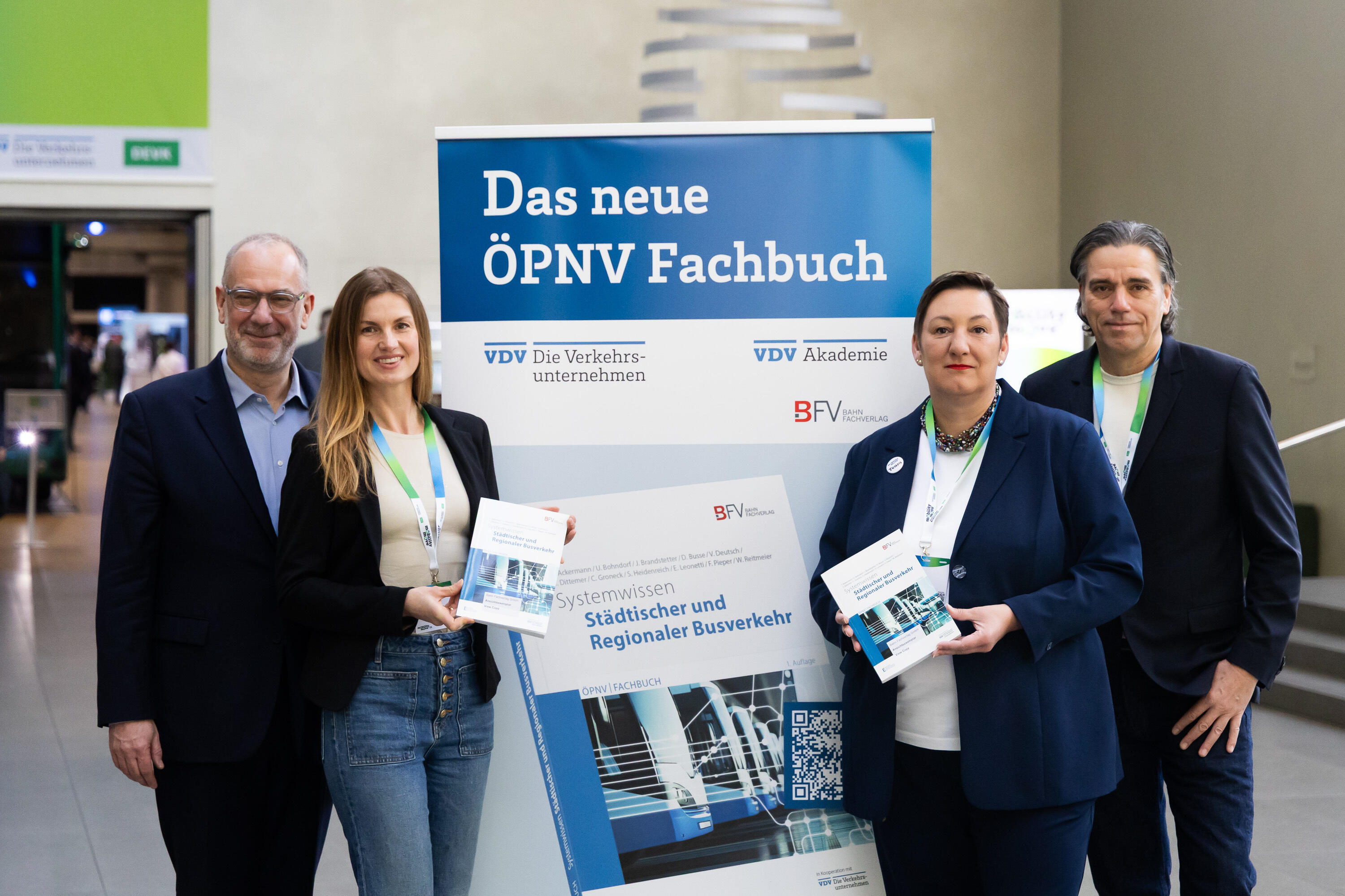 Vier Personen posieren in Reihe vor dem neuen ÖPNV Fachbuch: Alexander Möller (VDV-Akademie), Louisa Pabst (Bahn Fachverlag), Stefanie Menke (VDV-Akademie), Thorsten Breustedt (bahn Fachverlag)