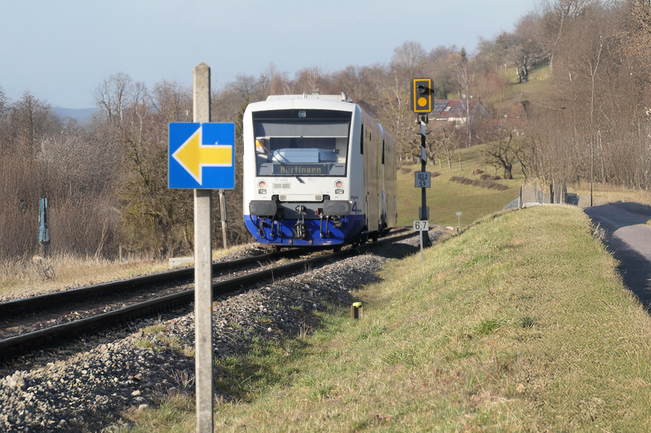 Nicht-elektrifizierter Zug fährt durch wenig besiedelte Landschaft.