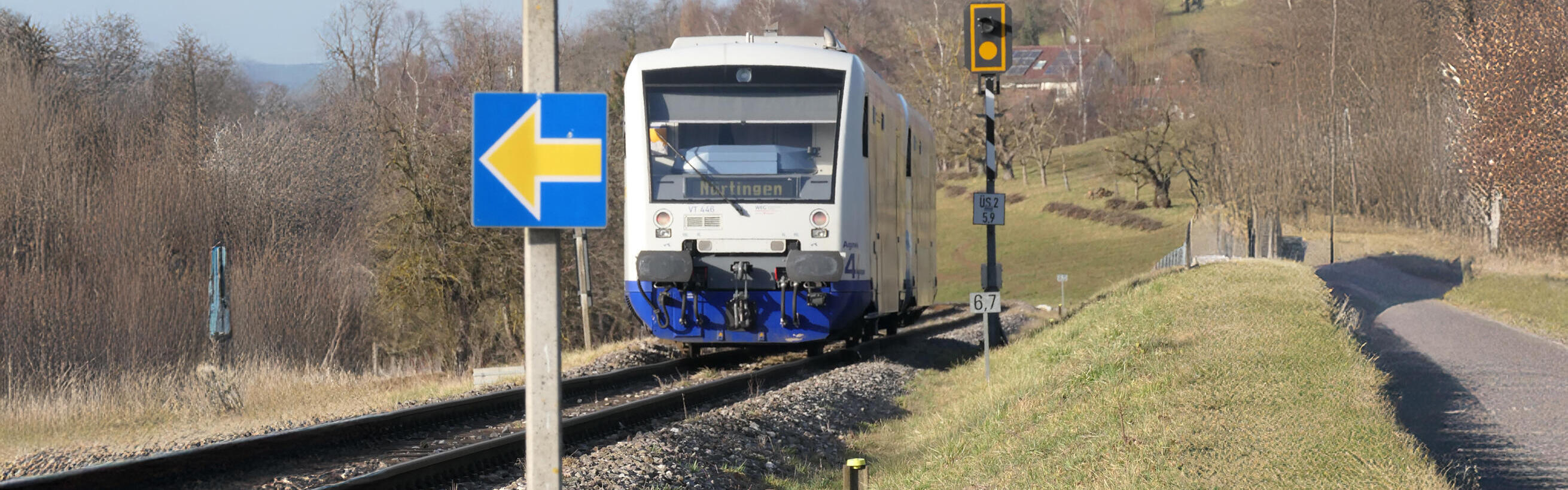 Nicht-elektrifizierter Zug fährt durch wenig besiedelte Landschaft.