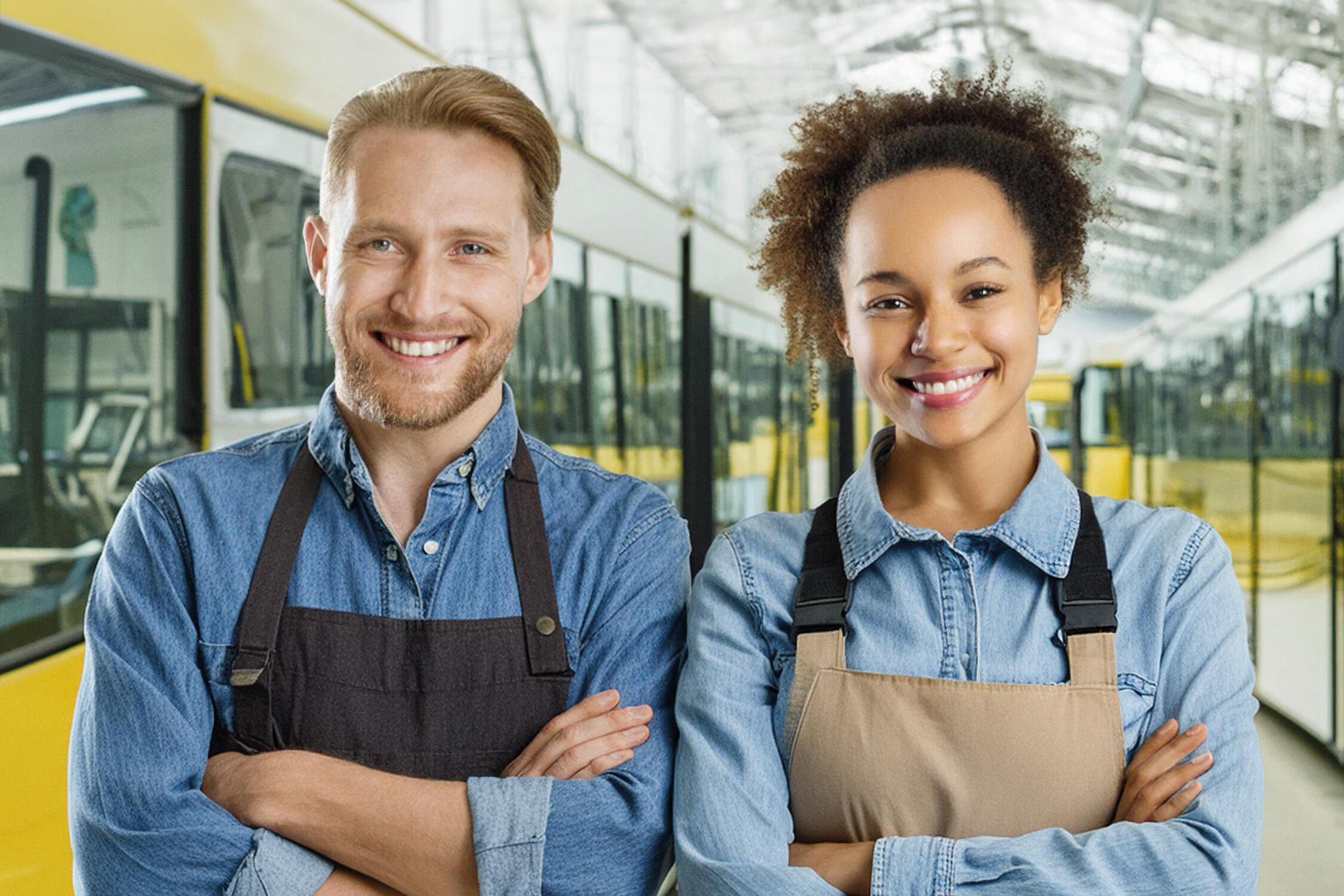 Zwei Werkstattmitarbeitende stehen zwischen Fahrzeugen in einer Abstellhalle