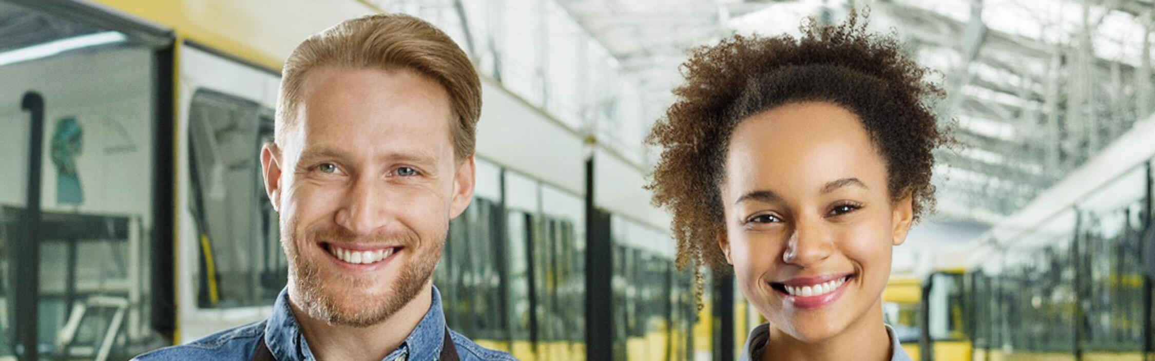 Zwei Werkstattmitarbeitende stehen zwischen Fahrzeugen in einer Abstellhalle