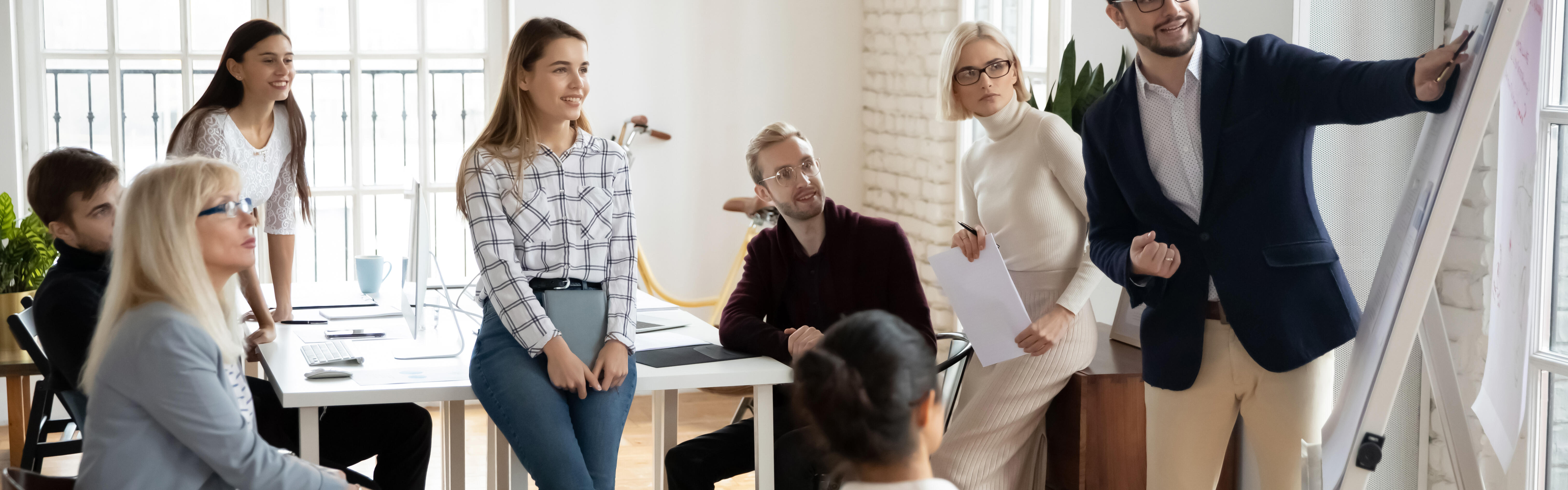 Eine kleine Gruppe glücklicher Menschen hört aufmerksam und motiviert einem Business-Coach zu.
