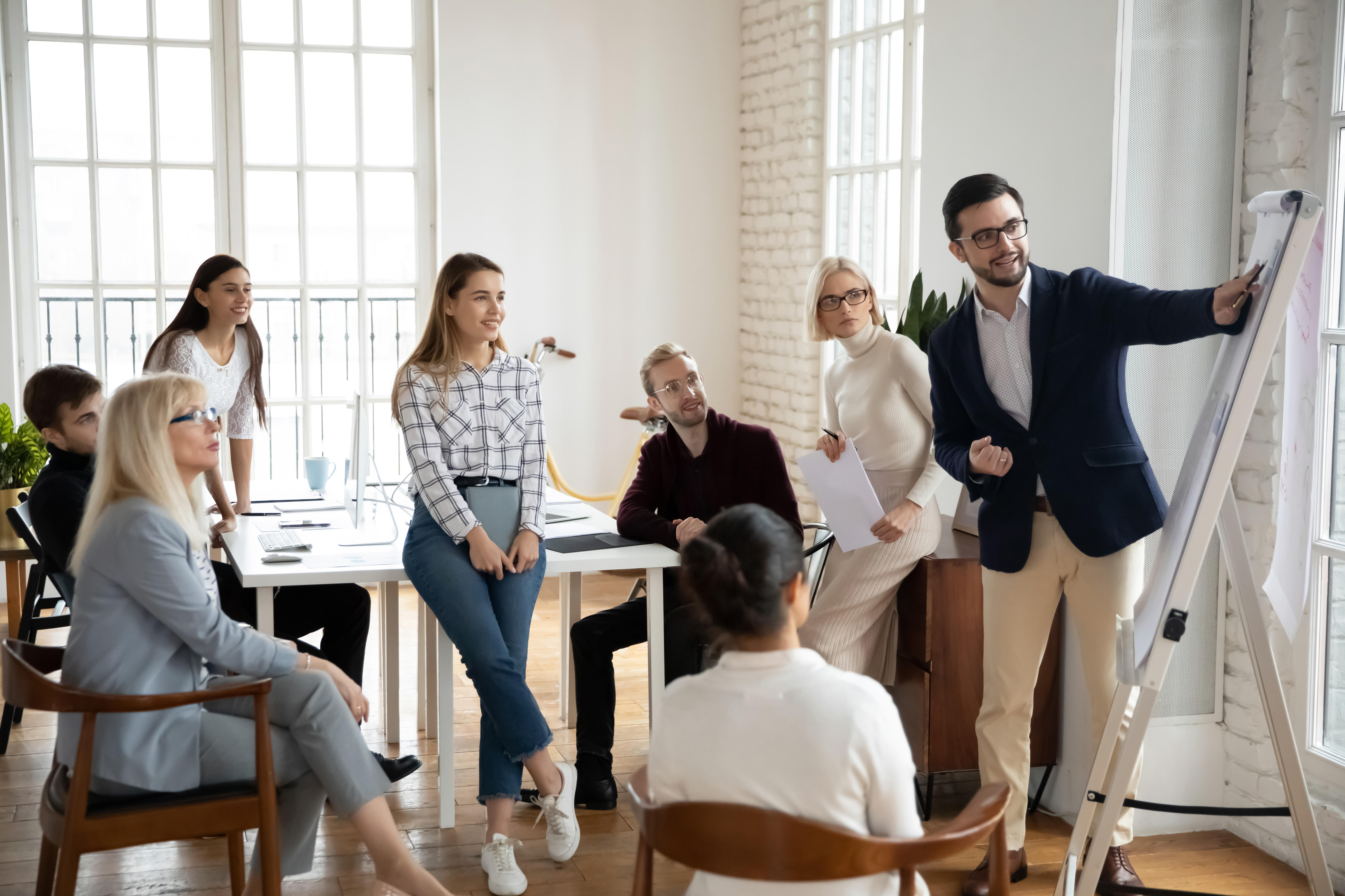 Eine kleine Gruppe glücklicher Menschen hört aufmerksam und motiviert einem Business-Coach zu.