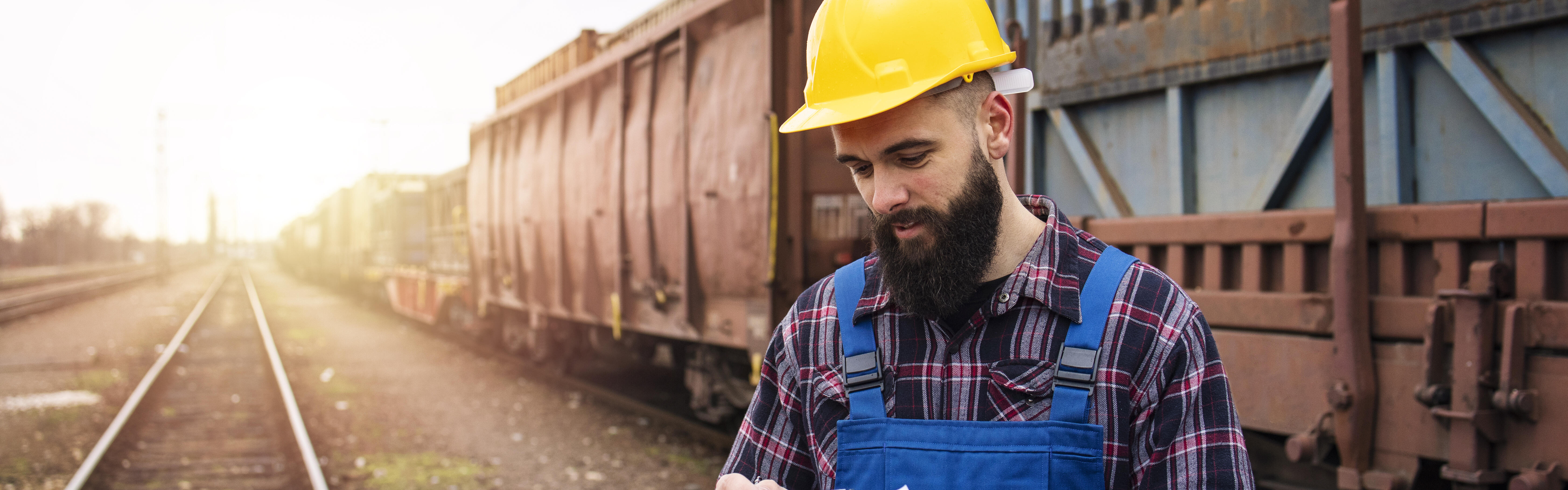 Mann kontrolliert Frachpapiere von Containern, die per Eisenbahn transportiert werden.