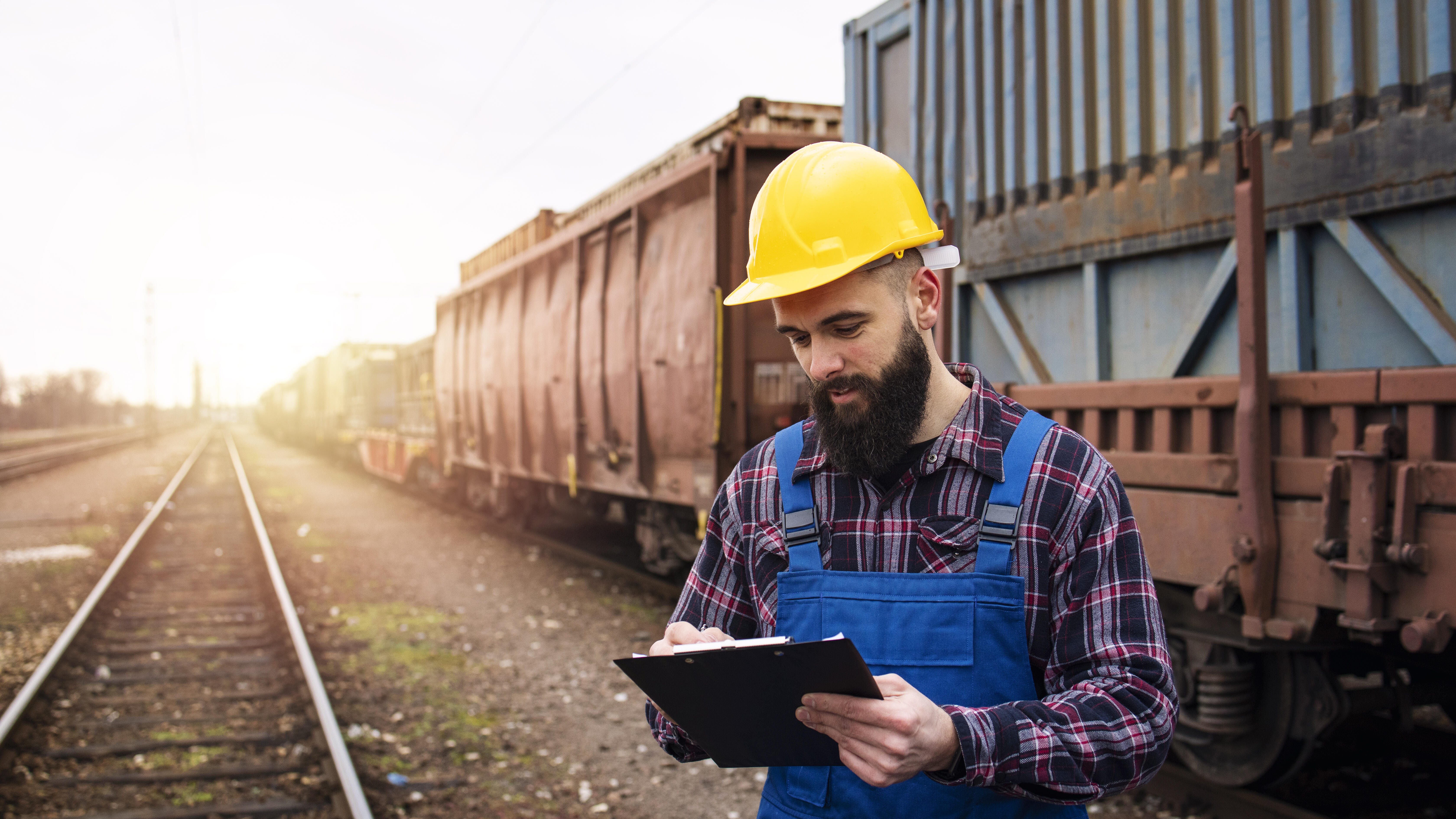 Mann kontrolliert Frachpapiere von Containern, die per Eisenbahn transportiert werden.