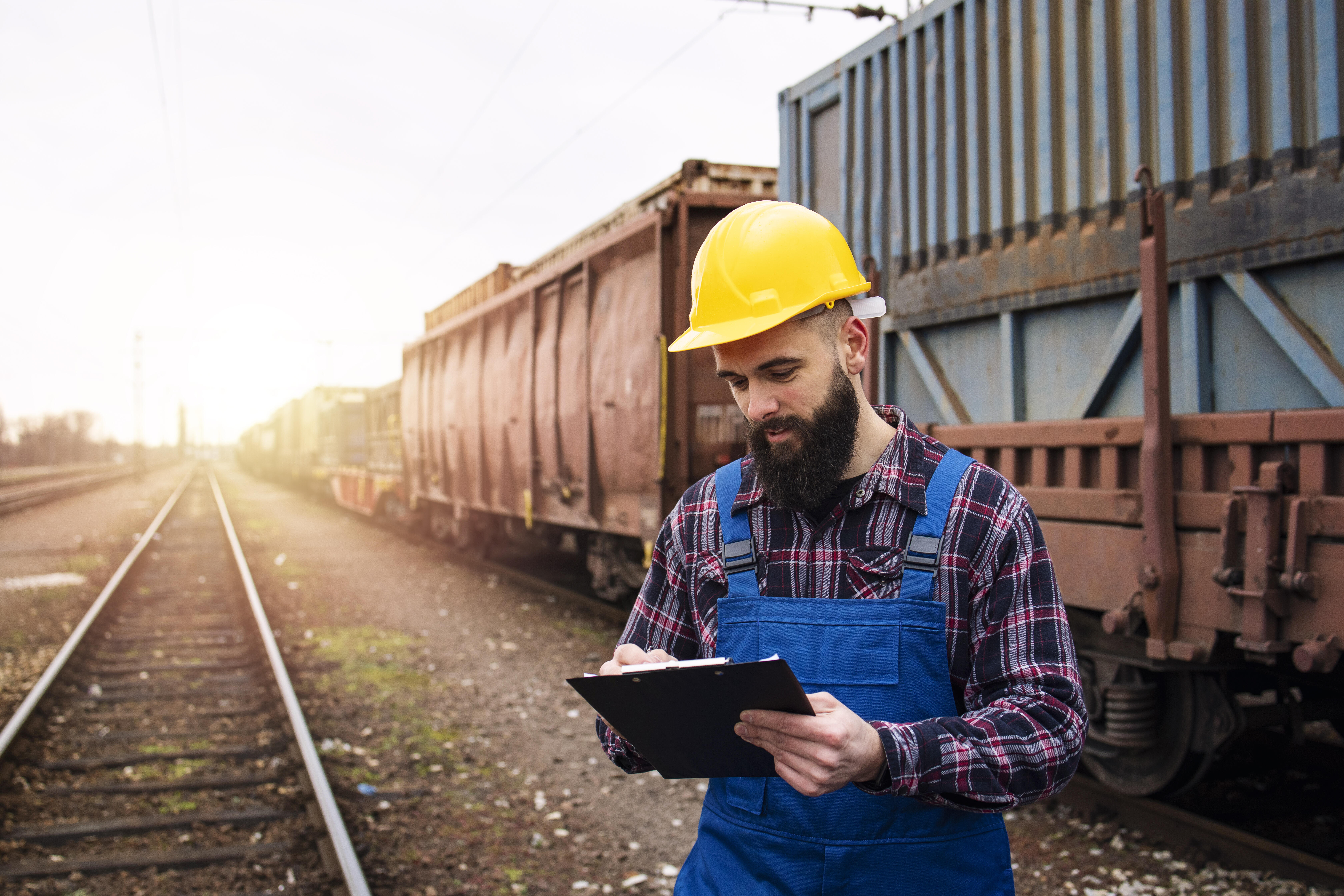 Mann kontrolliert Frachpapiere von Containern, die per Eisenbahn transportiert werden.
