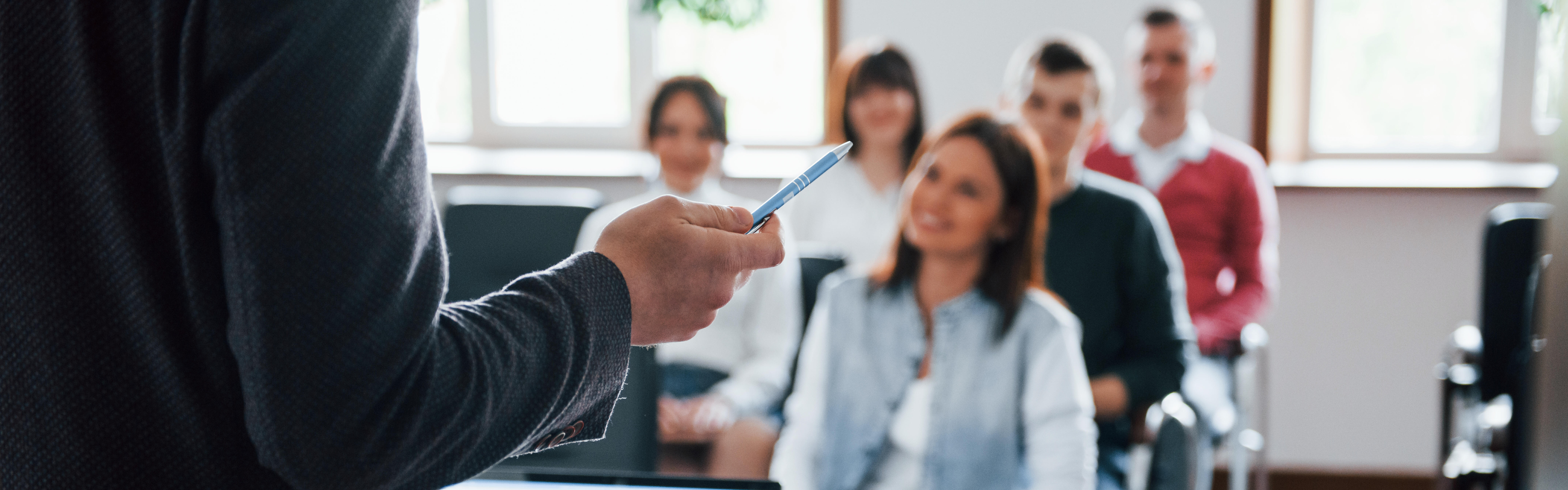 Gruppe von lächelnden Menschen bei einem Vortrag in einem modernen Raum.