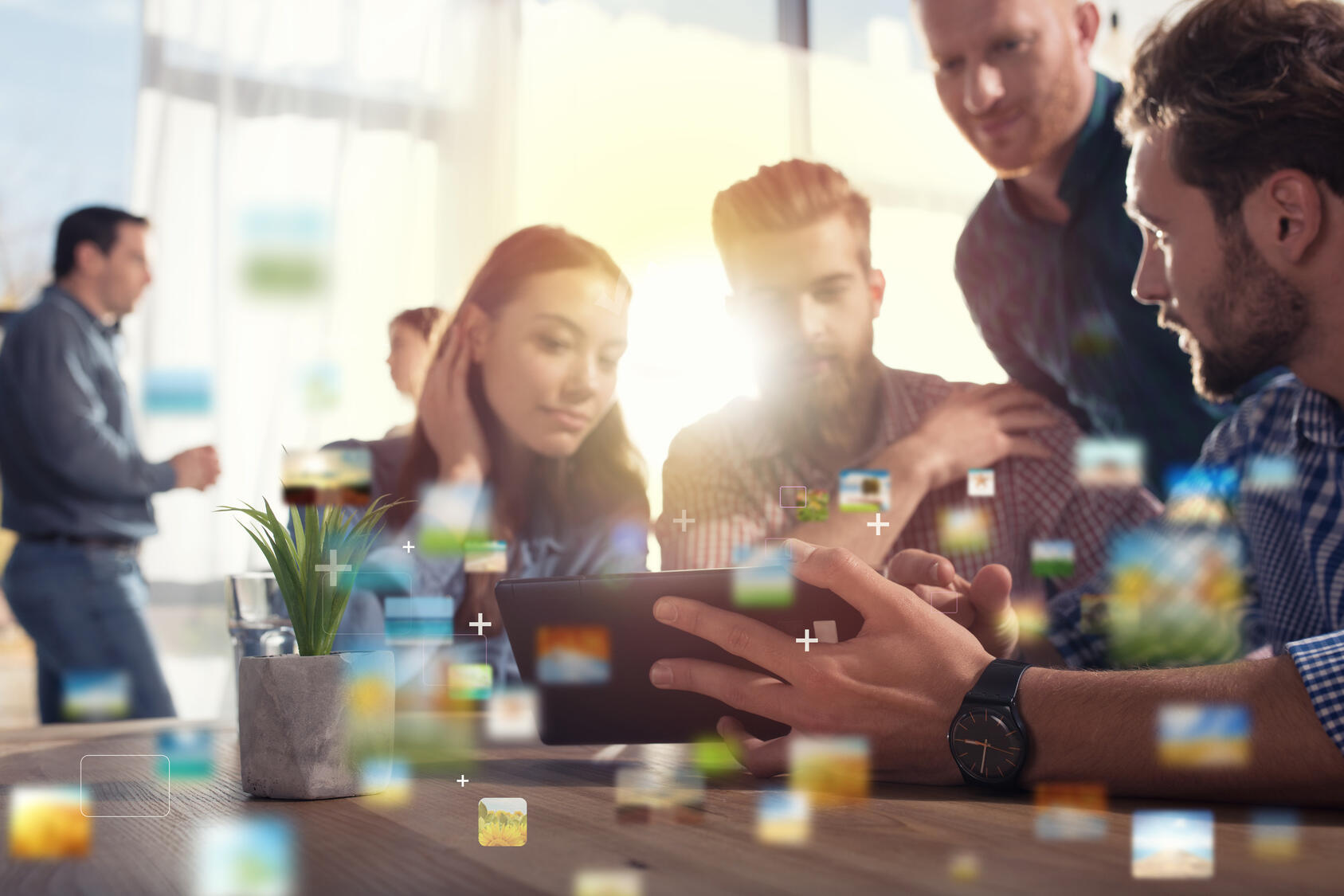 Eine Gruppe von Personen sitzt an einem Tisch und guckt auf ein Tablet.